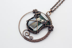 handmade circular pendant with copper wire wrapping and green and white fused glass