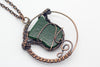 handmade circular pendant with copper wire wrapping and green and white fused glass