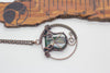 handmade circular pendant with copper wire wrapping and green and white fused glass