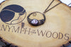 handmade circular pendant with copper wire wrapping and pink fused glass accent