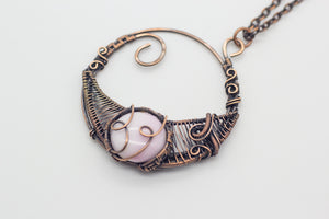 handmade circular pendant with copper wire wrapping and pink fused glass accent