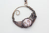 handmade circular pendant with copper wire wrapping and pink fused glass accent