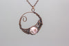 handmade circular pendant with copper wire wrapping and pink fused glass accent